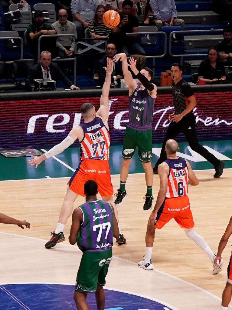 Tyler Kalinoski lanza de tres defendido por Thompkins